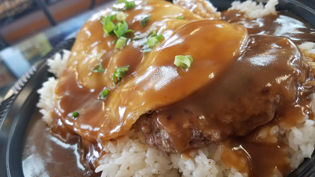A Hawaiʻi loco moco: white rice topped with a hamburger patty, fried egg, and brown gravy with green onions
