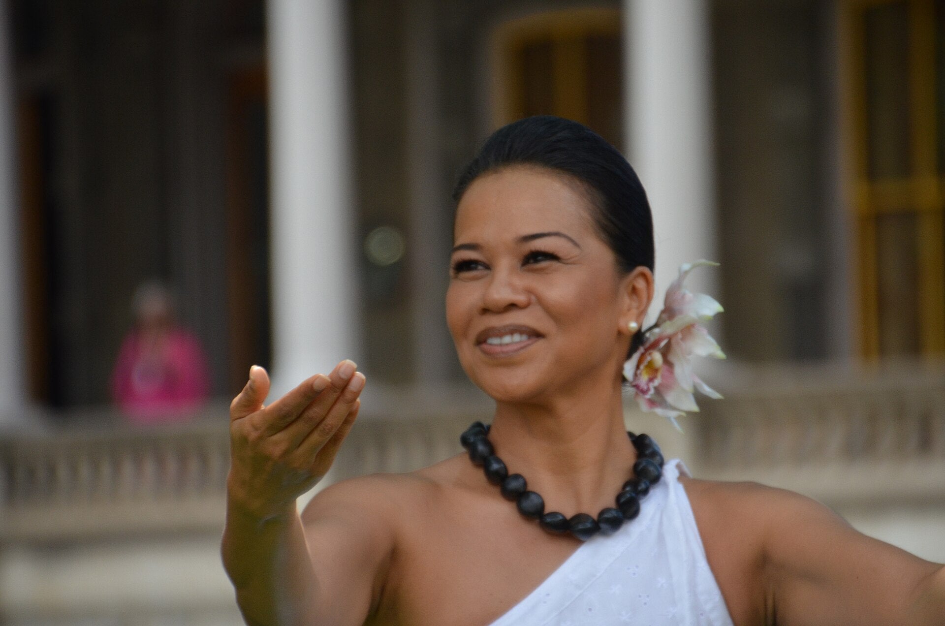 Hawaiian hula dancer performing with a graceful hand gesture, flower in her hair and kukui nut lei, Hawaiʻi
