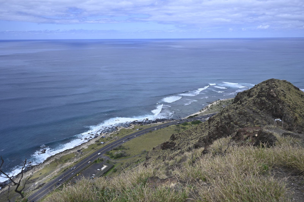 Aerial view of a coastal highway with cars along the Hawaiian shoreline