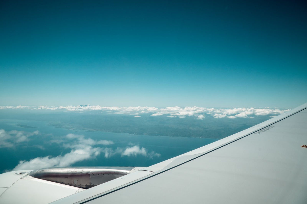 View from an airplane wing over the ocean and coastline on the long flight to Hawaiʻi