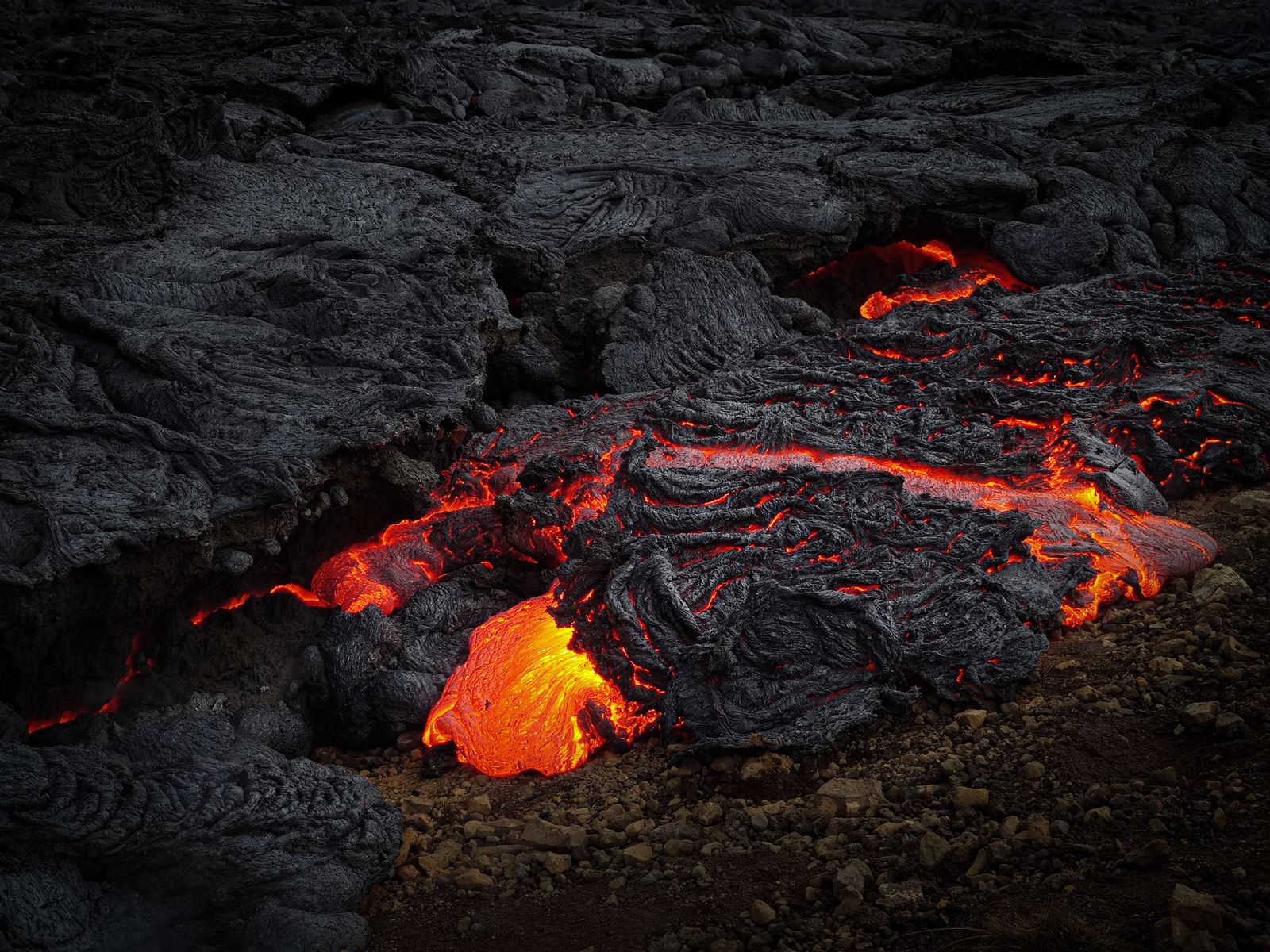 Molten lava flowing over volcanic rock in Hawaiʻi