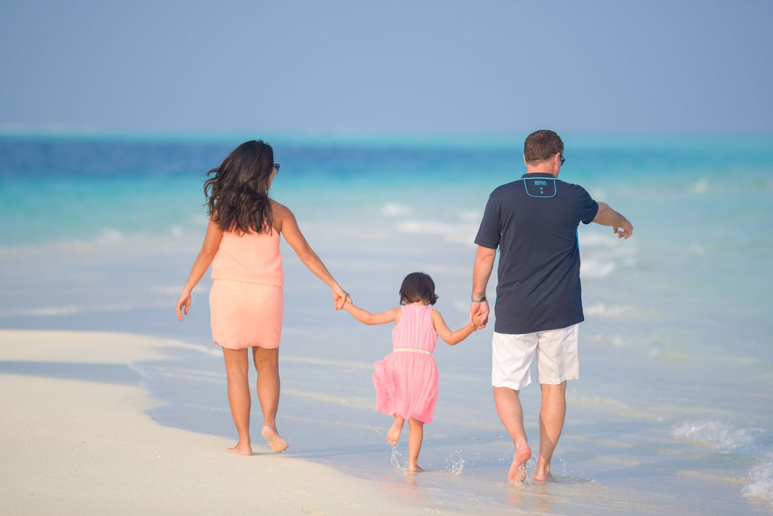 A family walking hand in hand along a tropical beach, evoking the meaning of ʻohana (family) in Hawaiʻi