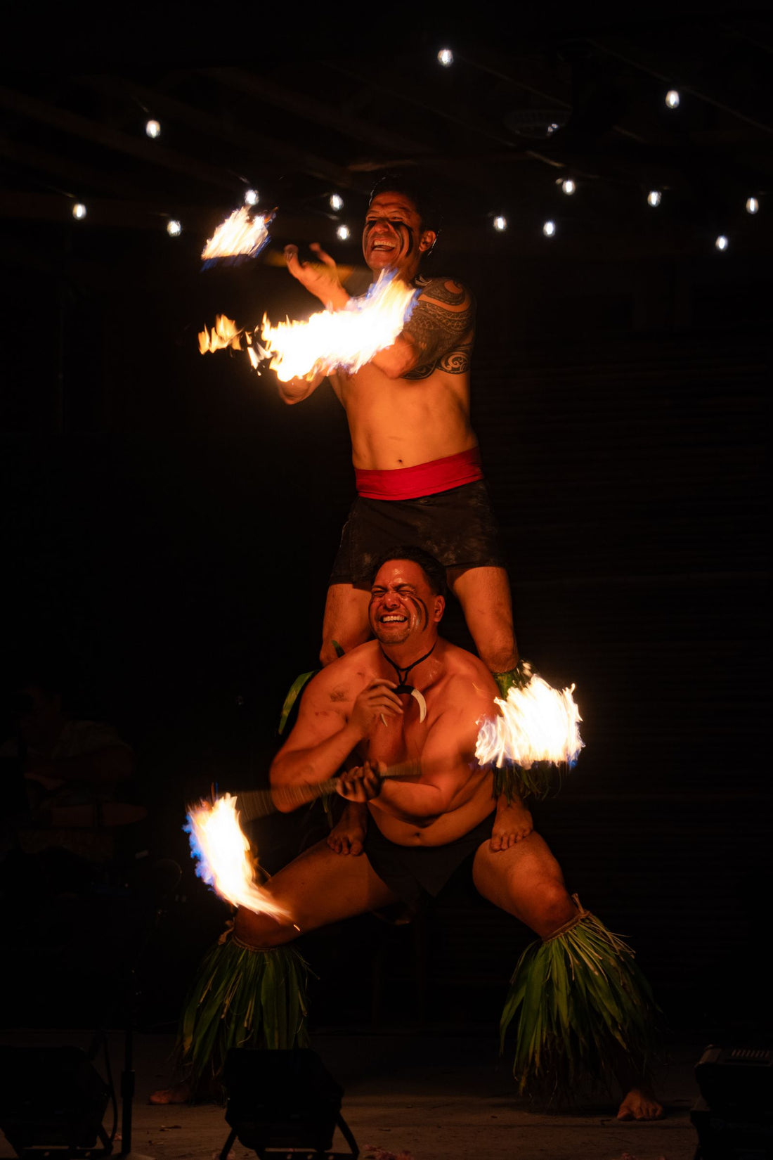 Fire-knife dancers performing at a nighttime lūʻau celebration in Hawaiʻi