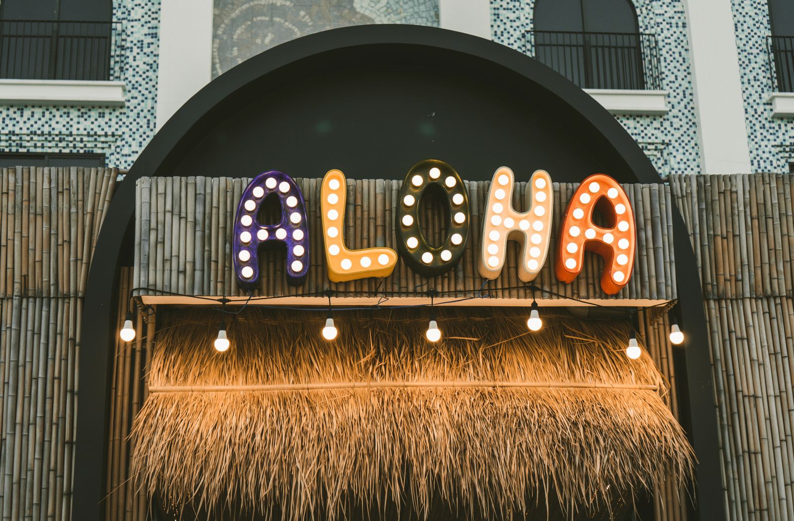 Colorful lit-up ALOHA sign with bamboo and thatch backdrop, Hawaiʻi