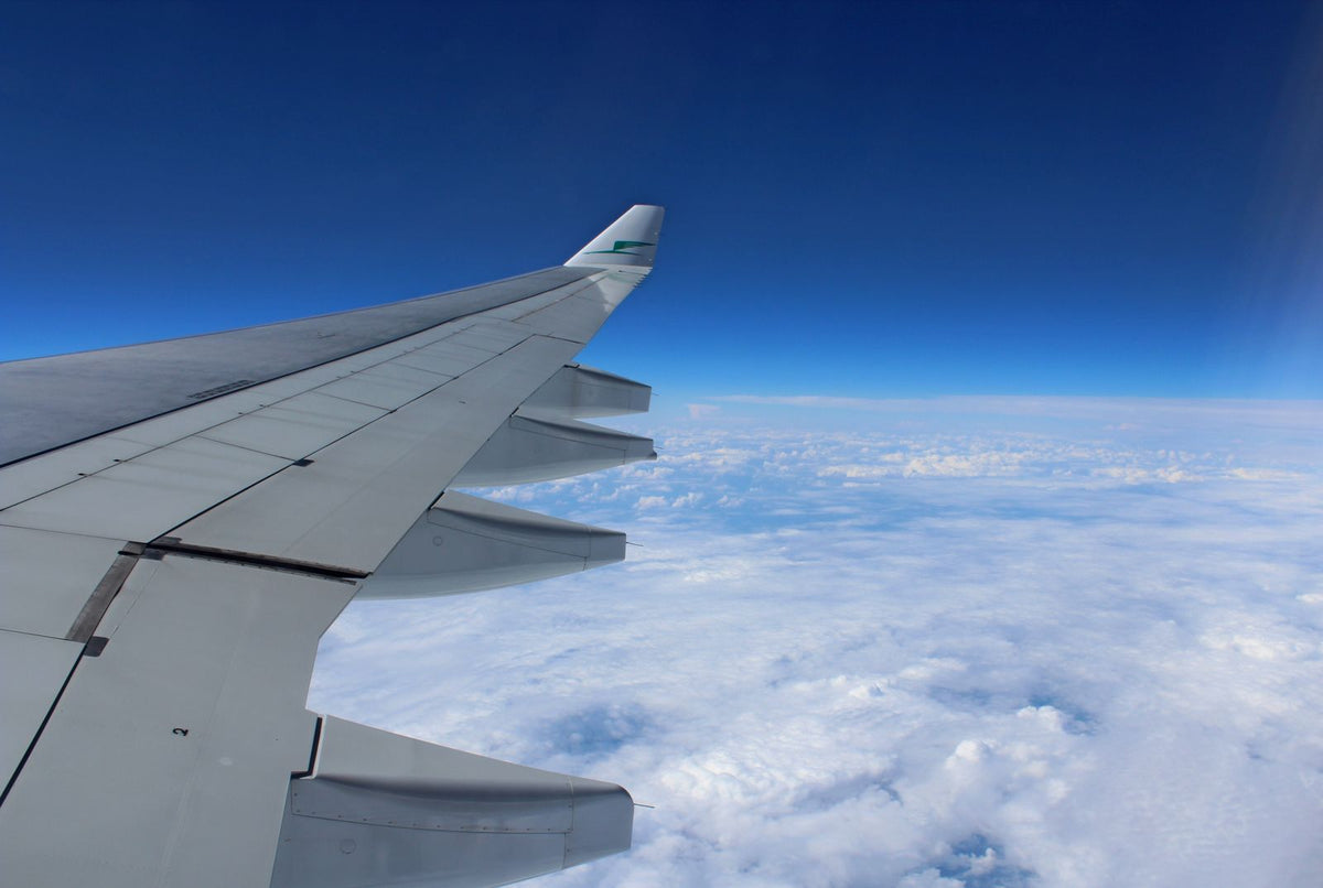 Airplane wing above the clouds on a long flight toward Hawaiʻi