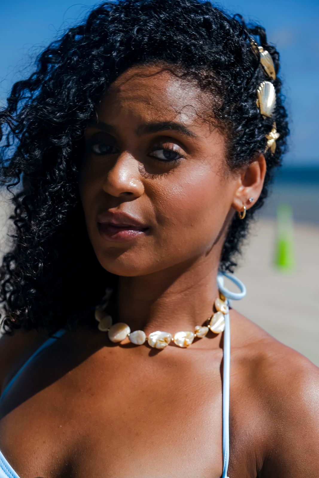 Woman wearing a puka-shell-style necklace made of small polished shell chips on a Hawaiian beach