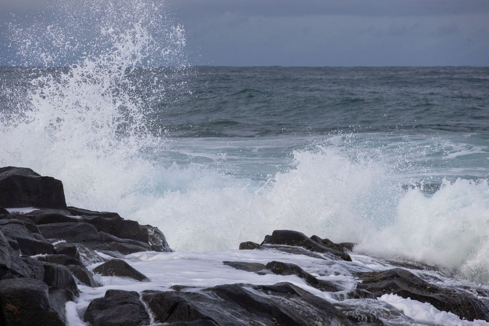 Waves break over black lava rock on the Hawaiian coast