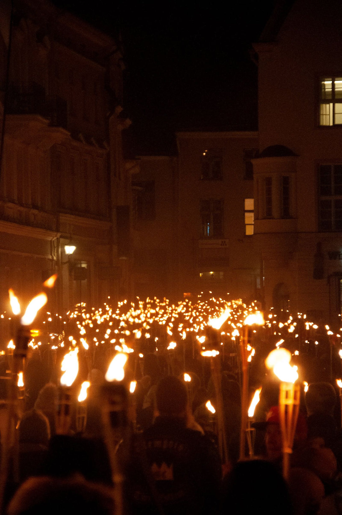A nighttime torchlight procession glowing in the dark, evoking the huakaʻi pō — the Night Marchers of Hawaiian legend in Hawaiʻi