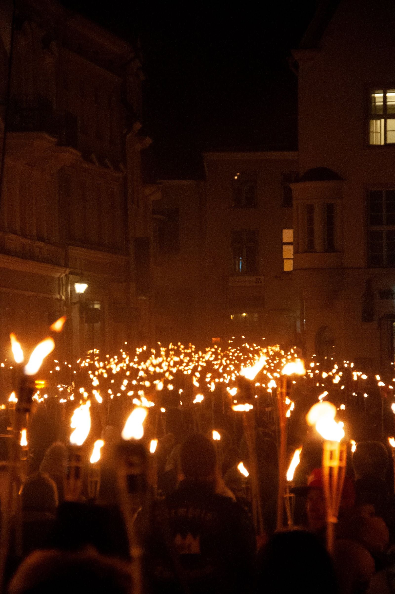 A nighttime torchlight procession glowing in the dark, evoking the huakaʻi pō — the Night Marchers of Hawaiian legend in Hawaiʻi