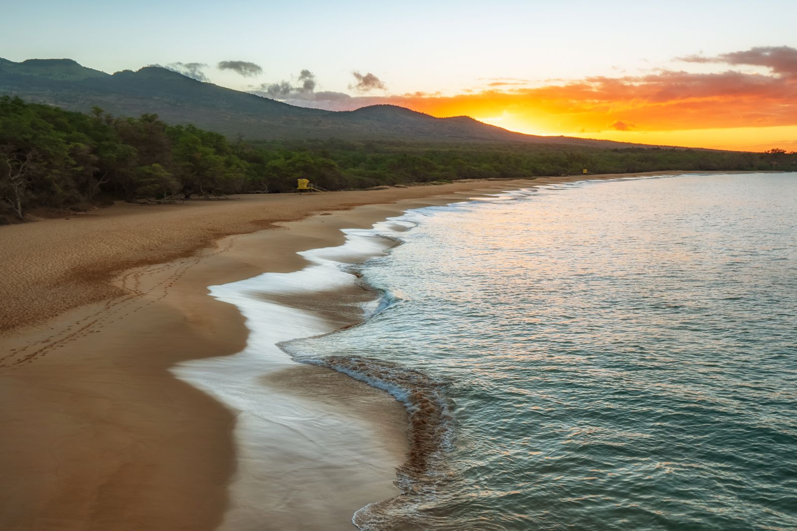 Sunset over a Maui, Hawaii beach with mountains in the background