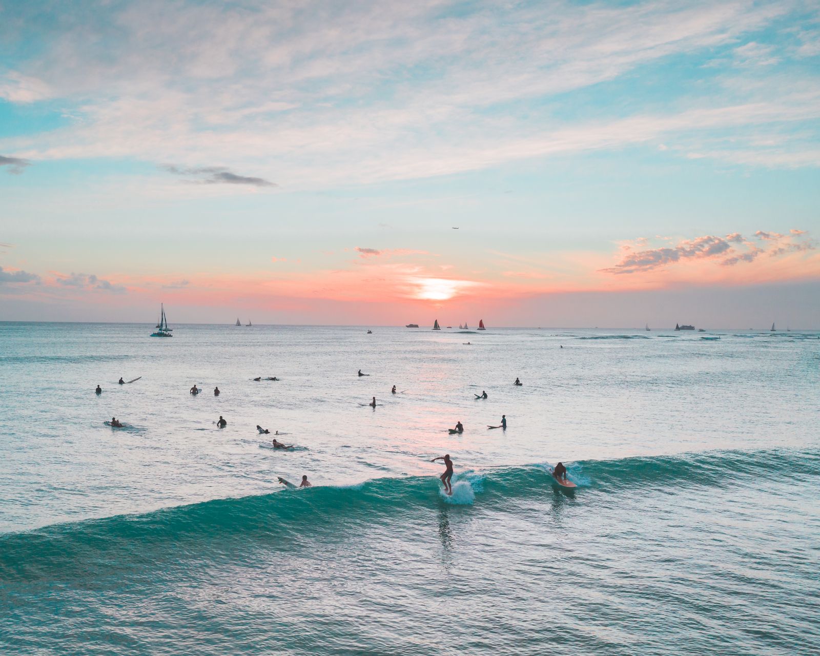 Surfers at sunset in the ocean off Waikīkī, Hawaiʻi