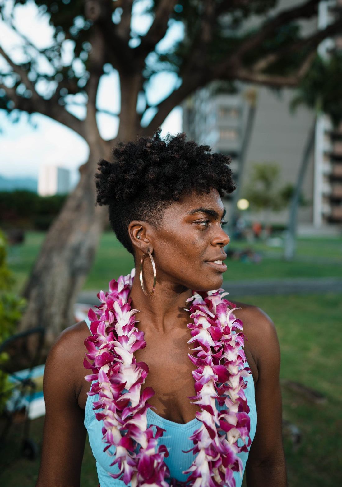 A woman wearing a purple and white orchid lei in a Honolulu park in Hawaiʻi