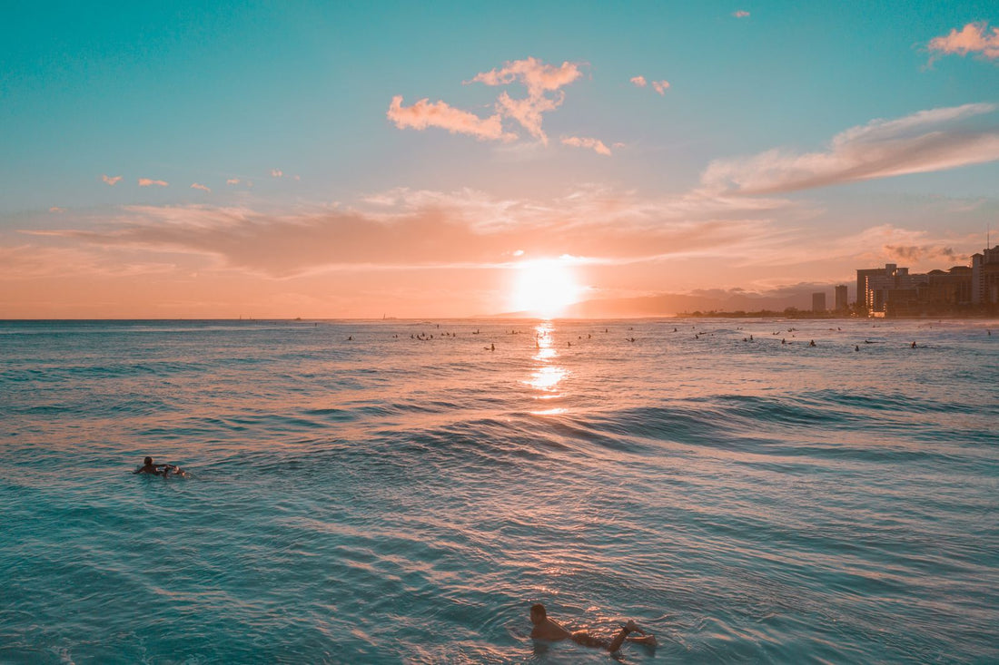 Sunset over the ocean at Waikiki Beach with surfers in the water, Hawaiʻi