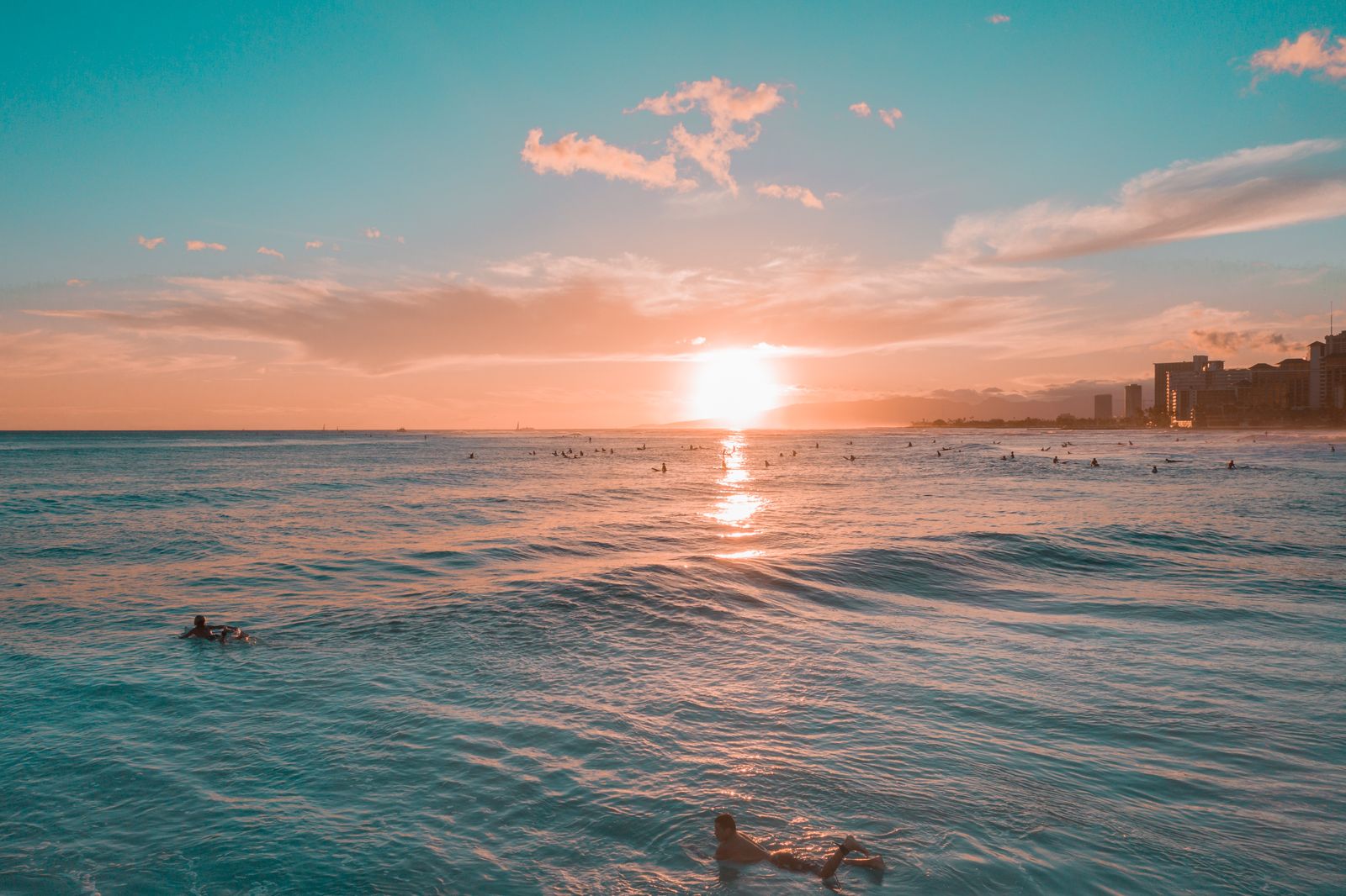Sunset over the ocean at Waikiki Beach with surfers in the water, Hawaiʻi