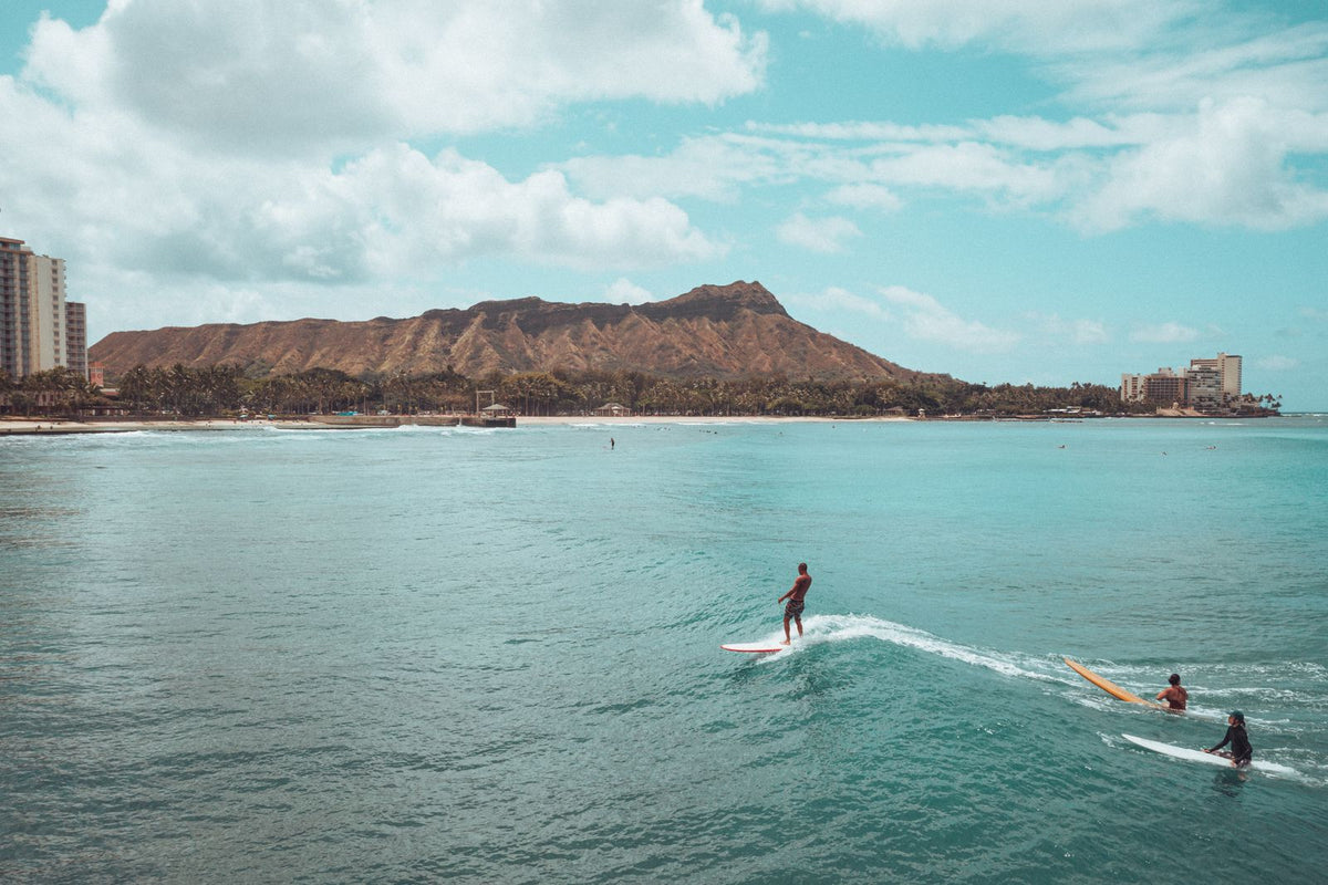 Surfers riding gentle waves at Waikiki Beach with Diamond Head in the background, Hawaiʻi