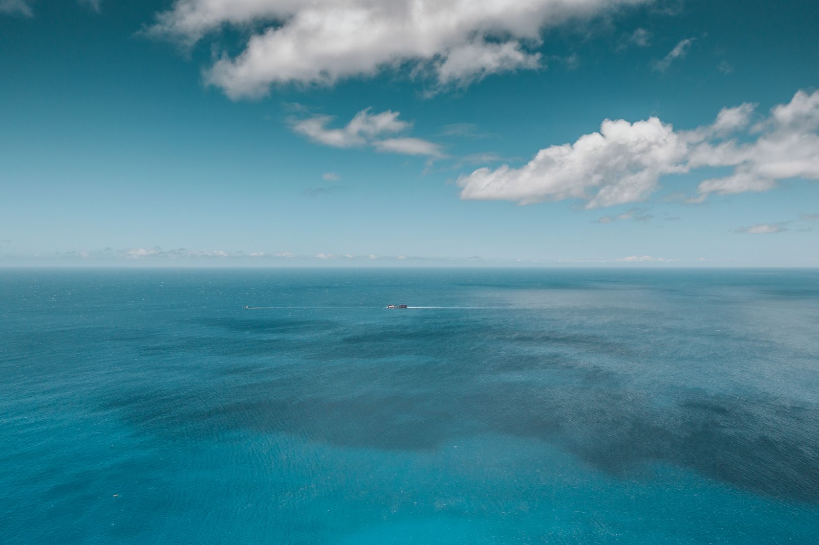 Aerial view of the vast open Pacific Ocean with scattered clouds near Hawaiʻi
