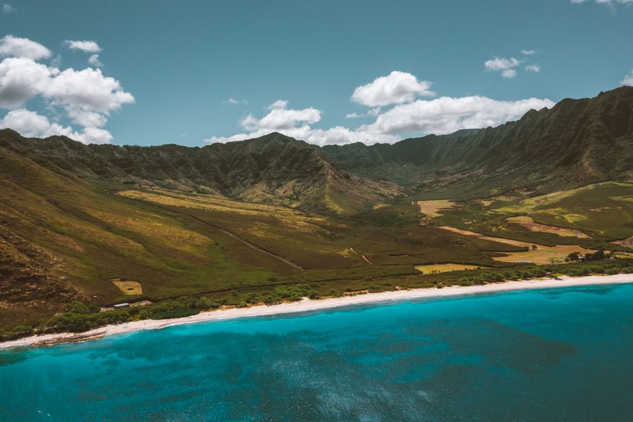 Aerial view of a Hawaiian valley sloping from mountains to a turquoise bay, illustrating the mauka-to-makai ahupuaʻa land division