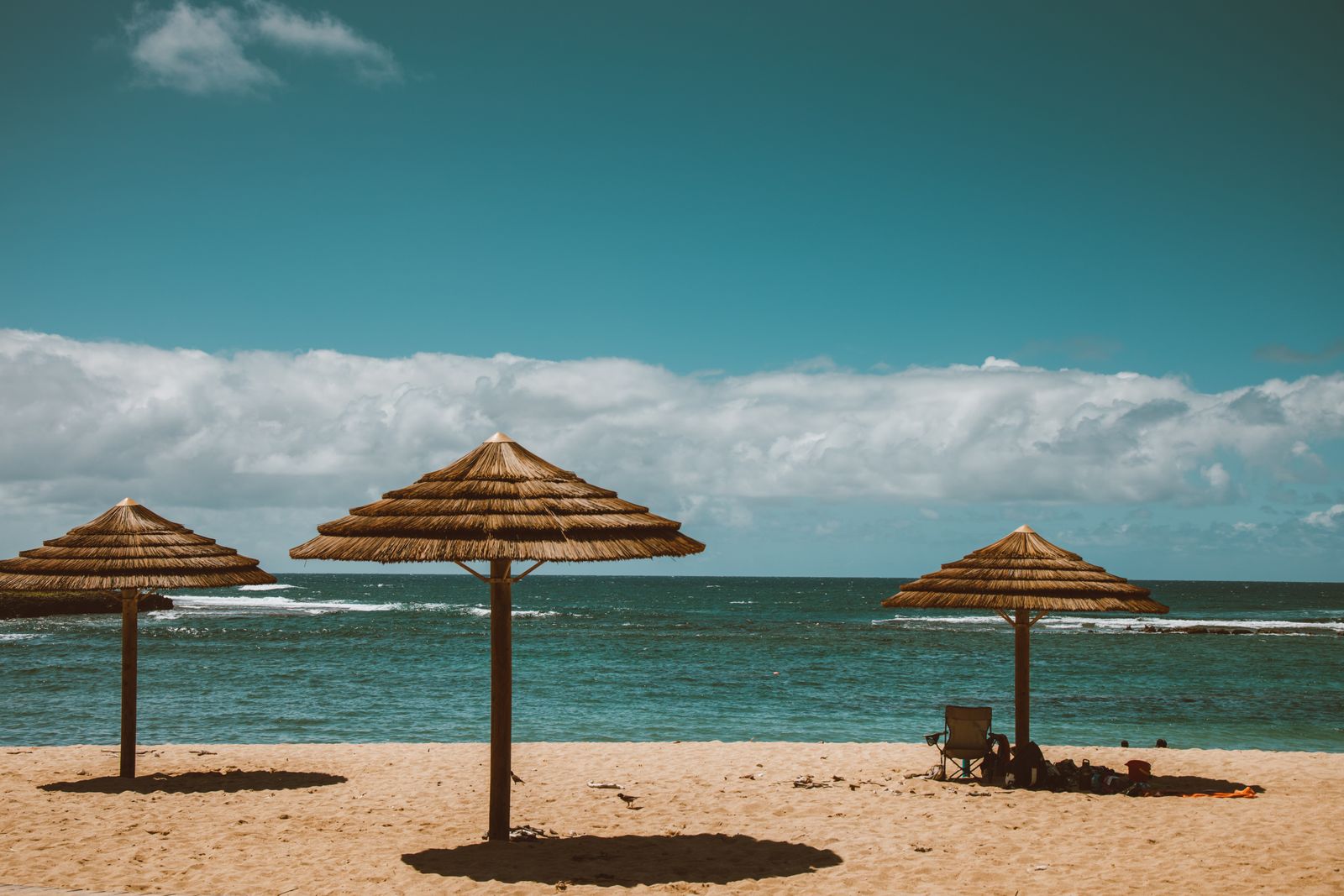 Thatched beach umbrellas on a Hawaiian shoreline, Hawaiʻi