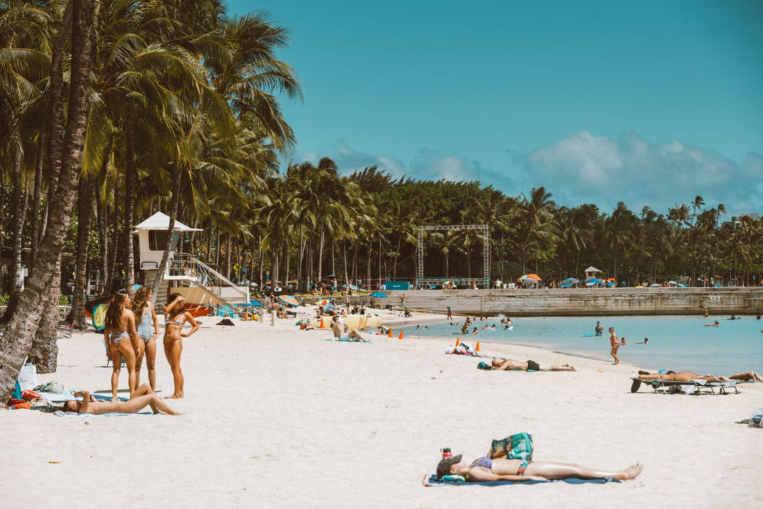 Crowded tropical beach with palm trees and sunbathers in Hawaiʻi