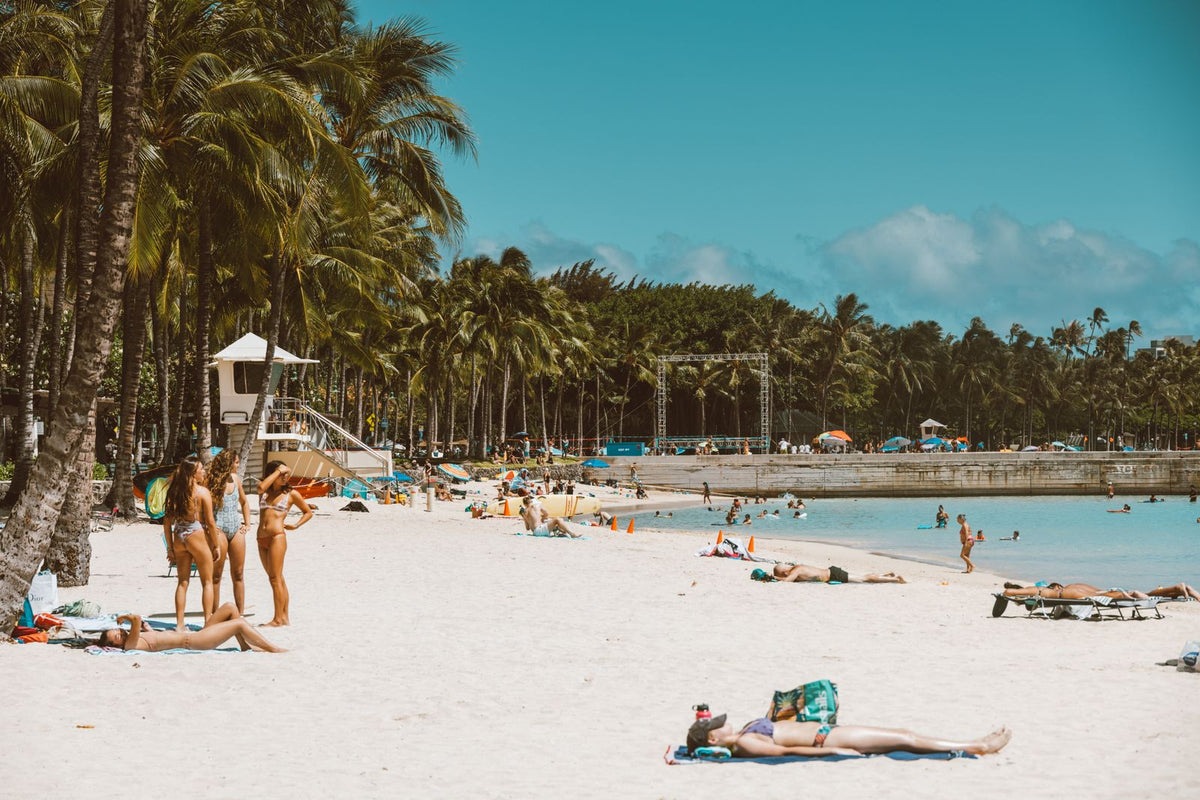Crowded tropical beach with palm trees and sunbathers in Hawaiʻi