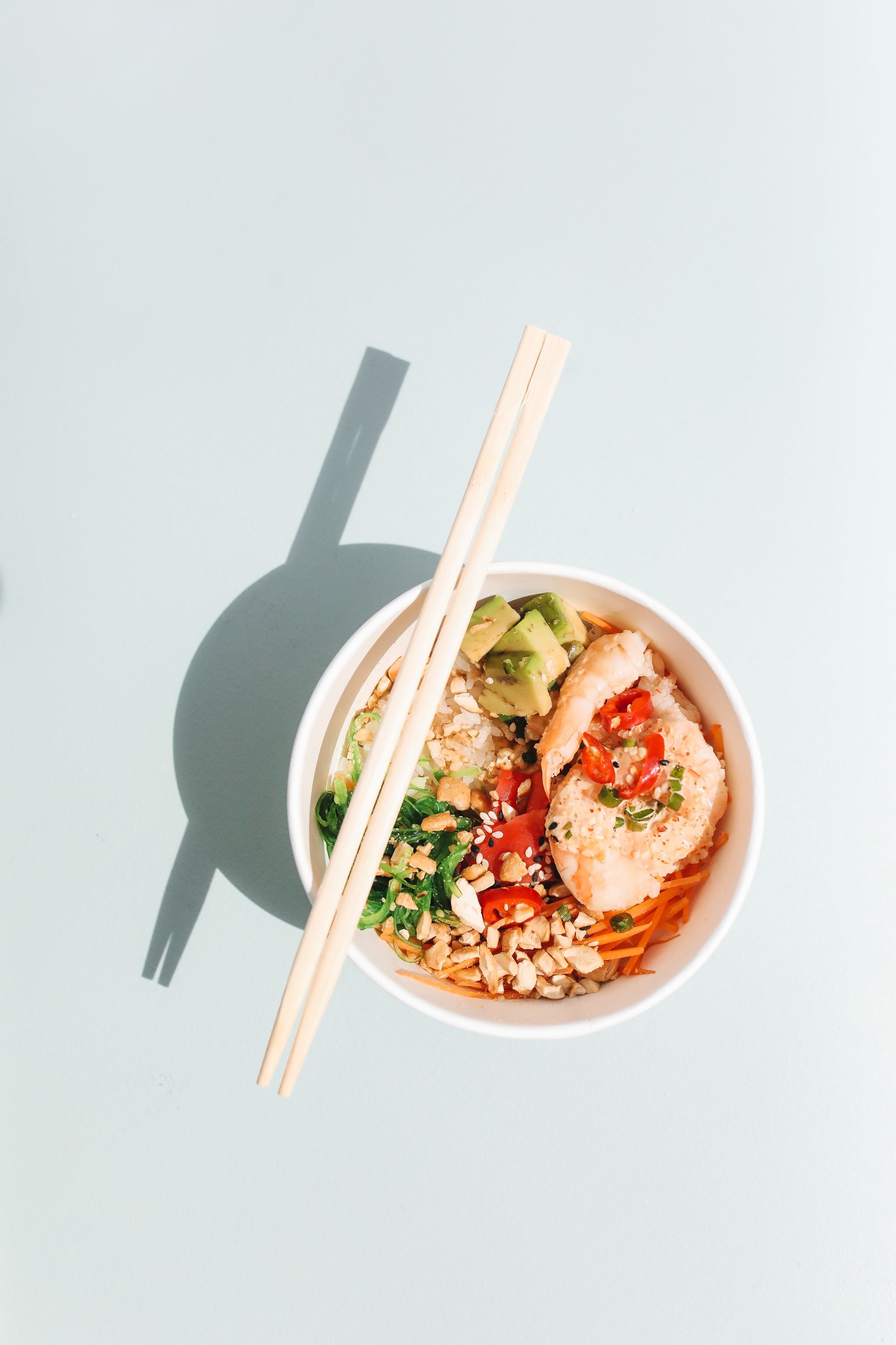 Overhead view of a fresh poke bowl with chopsticks, a beloved Hawaiian food, Hawaiʻi