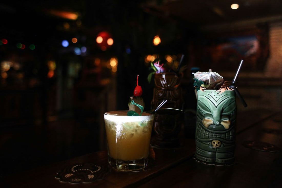 Tiki mugs and a mai tai cocktail on a bar counter, Hawaiʻi tiki style