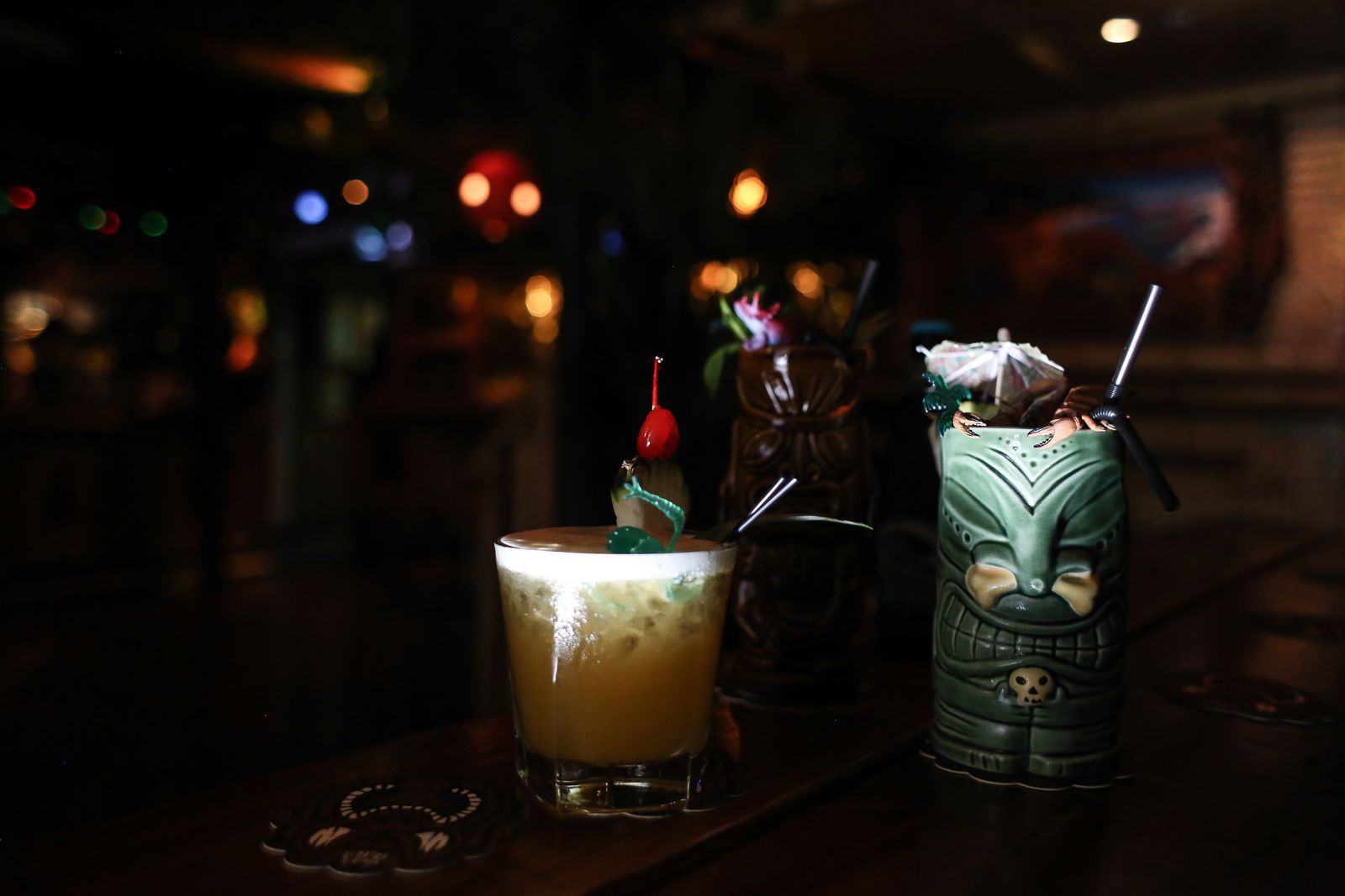Tiki mugs and a mai tai cocktail on a bar counter, Hawaiʻi tiki style