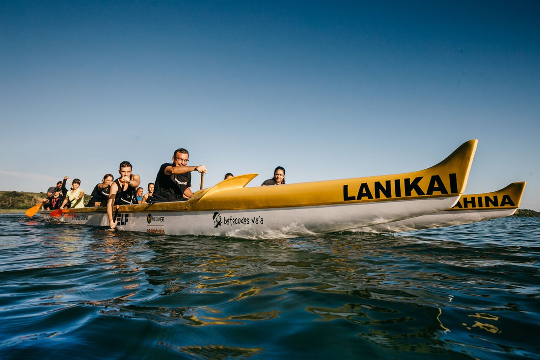 Hawaiian outrigger canoe crew paddling a waʻa together on the ocean, Hawaiʻi