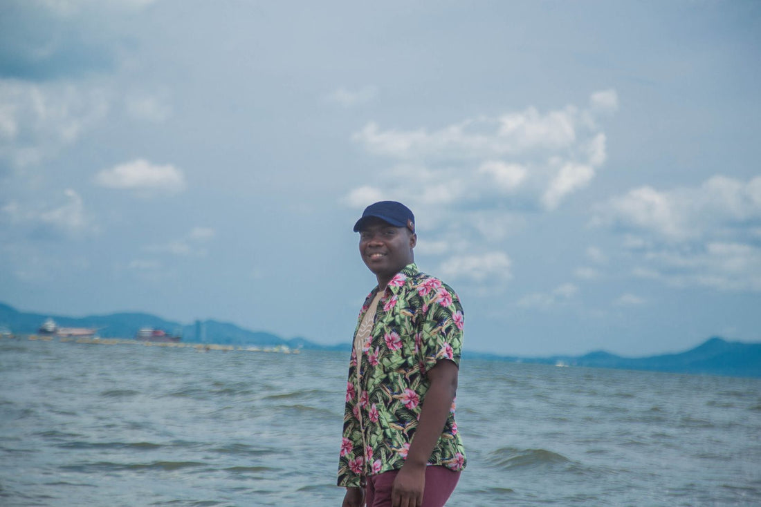 Man in a tropical floral shirt standing by the ocean in Hawaiʻi