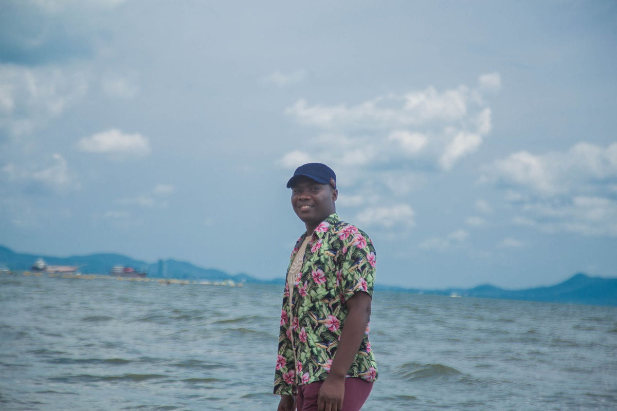 Man in a tropical floral shirt standing by the ocean in Hawaiʻi