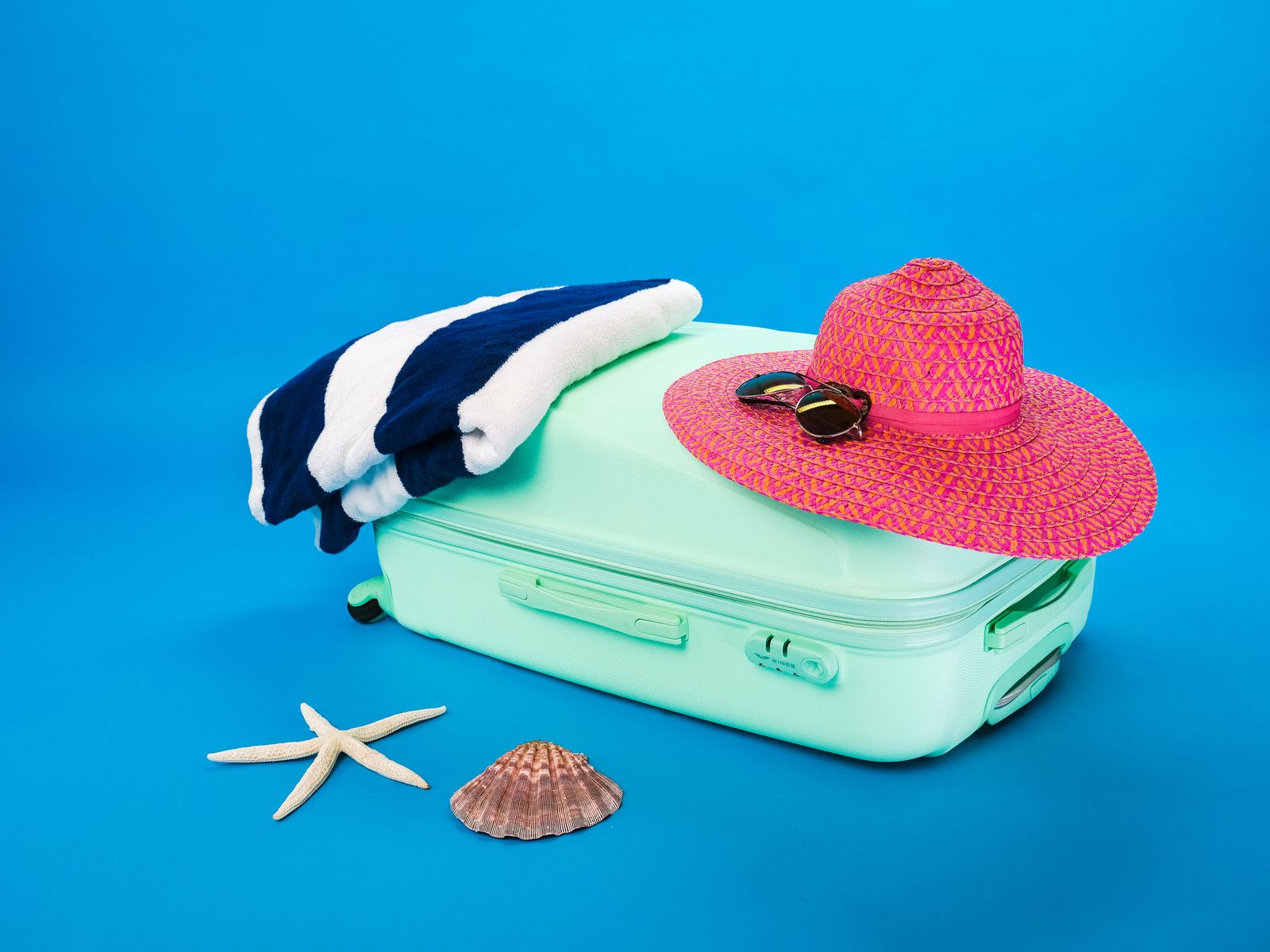 Packed beach suitcase with sun hat, sunglasses, towel, starfish and seashell, ready for a Hawaiʻi trip