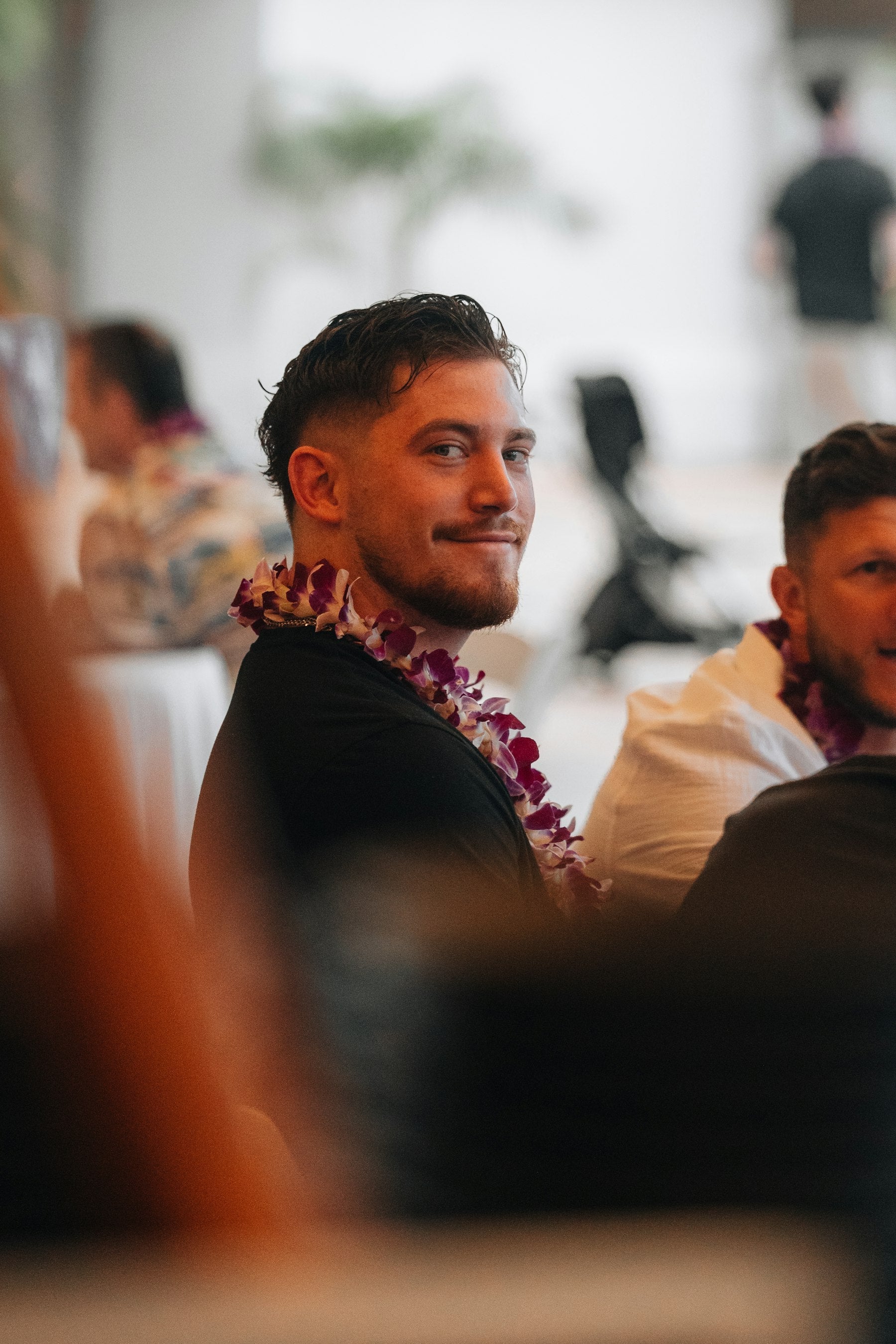 A man wearing a fresh flower lei smiles, a traditional Hawaiian welcome